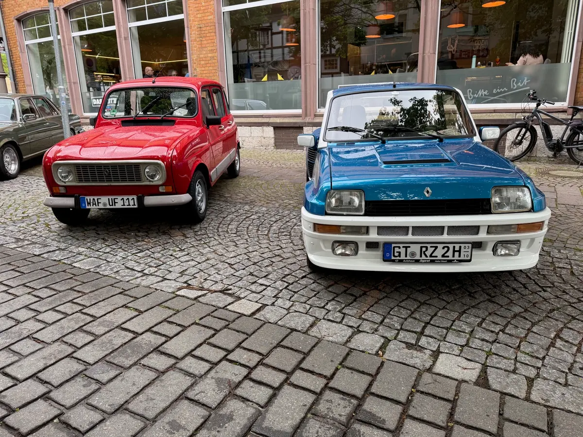 Frontalansicht: ein roter Renault 4 neben einem blau-weißen Renault 5 Turbo vor einem Café in der Haller Altstadt