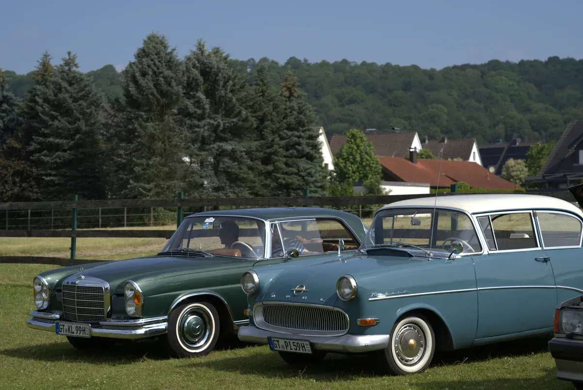 Mercedes W111 und Opel Rekord nebeneinander auf der Wiese