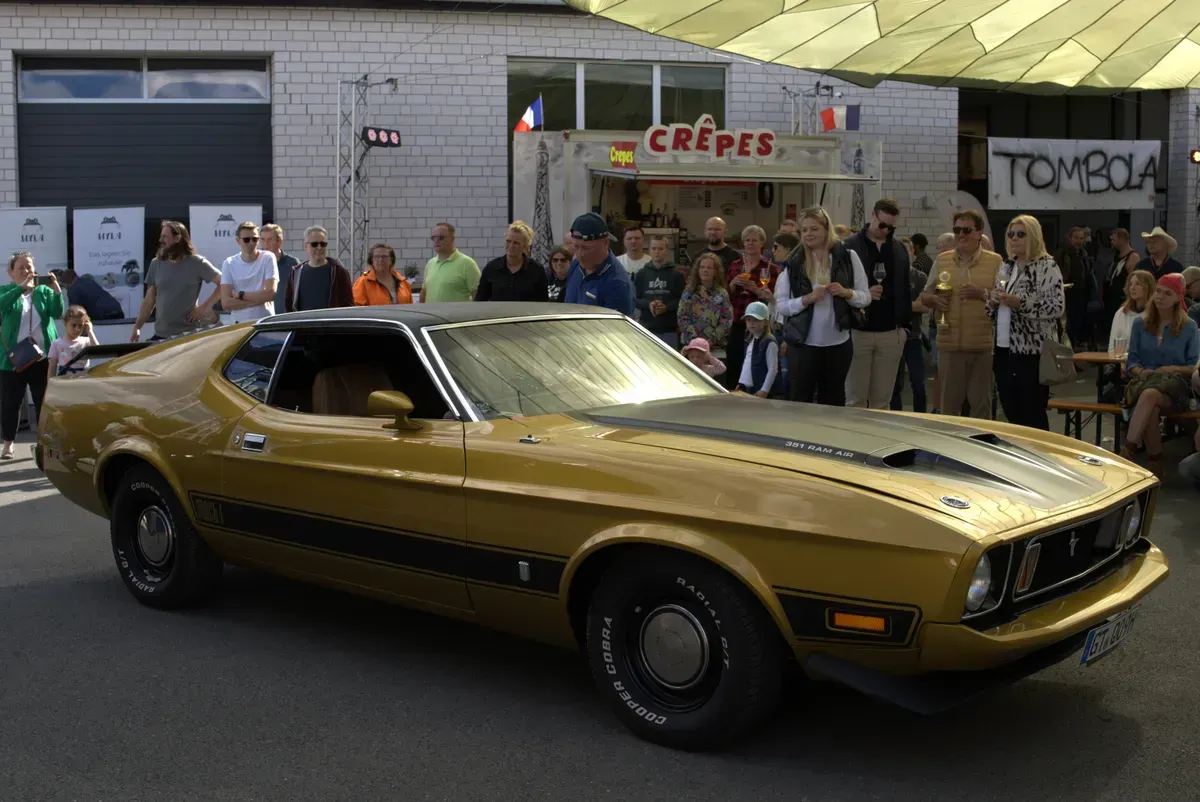 Ford Mustang Mach 1 in Gold bei der Fahrzeugparade vor begeistertem Publikum
